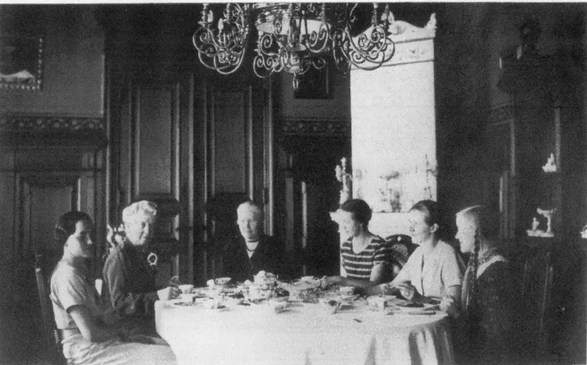 Jadalnia przed 1945 r. z piecem kaflowym i żyrandolem – panie z rodziny przy stole kawowym (kronika rodzinna)