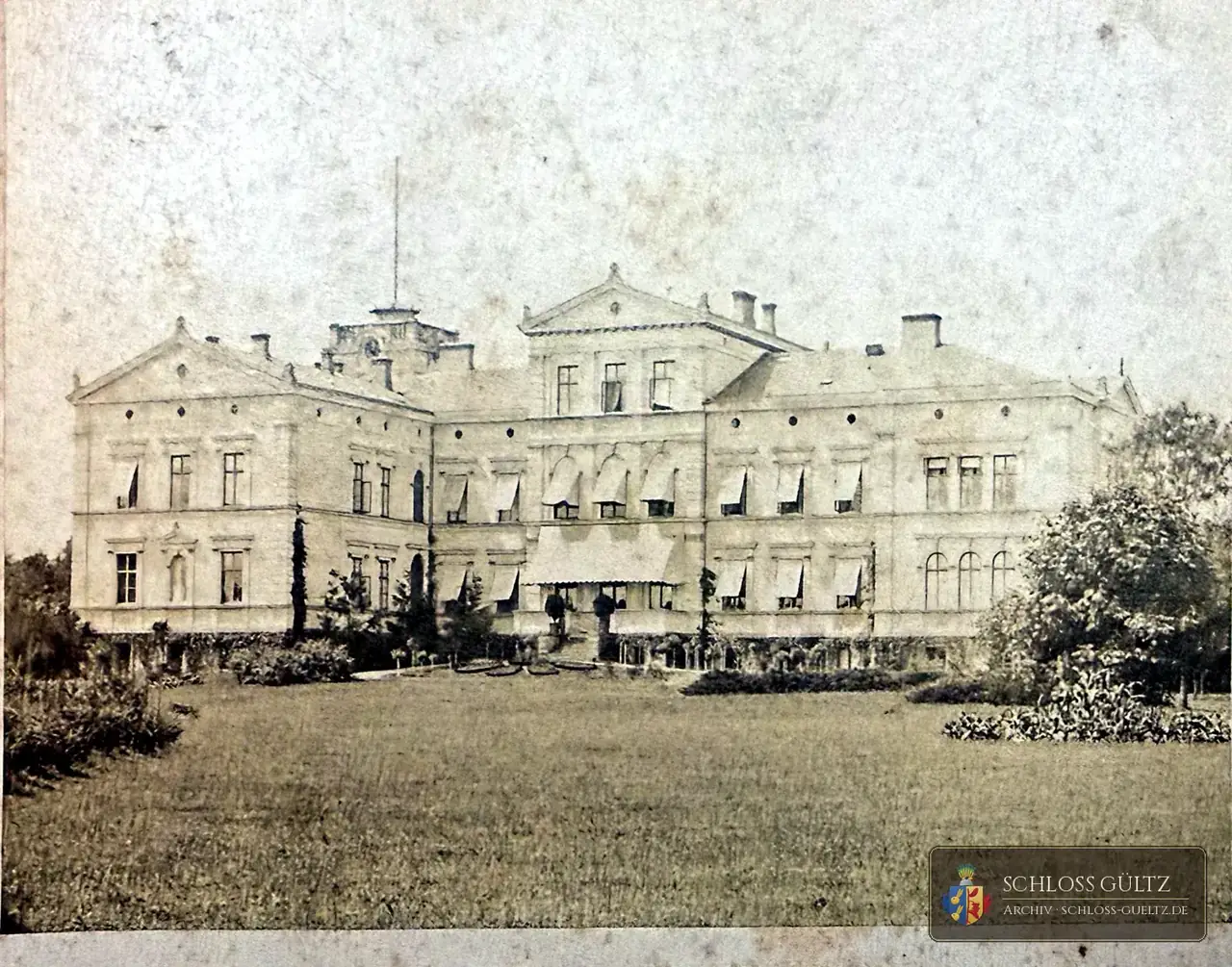 Frühe Fotografie der Parkseite von Schloss Gültz mit Markisen an den Fenstern, Terrasse und Turm, davor eine weite Rasenfläche