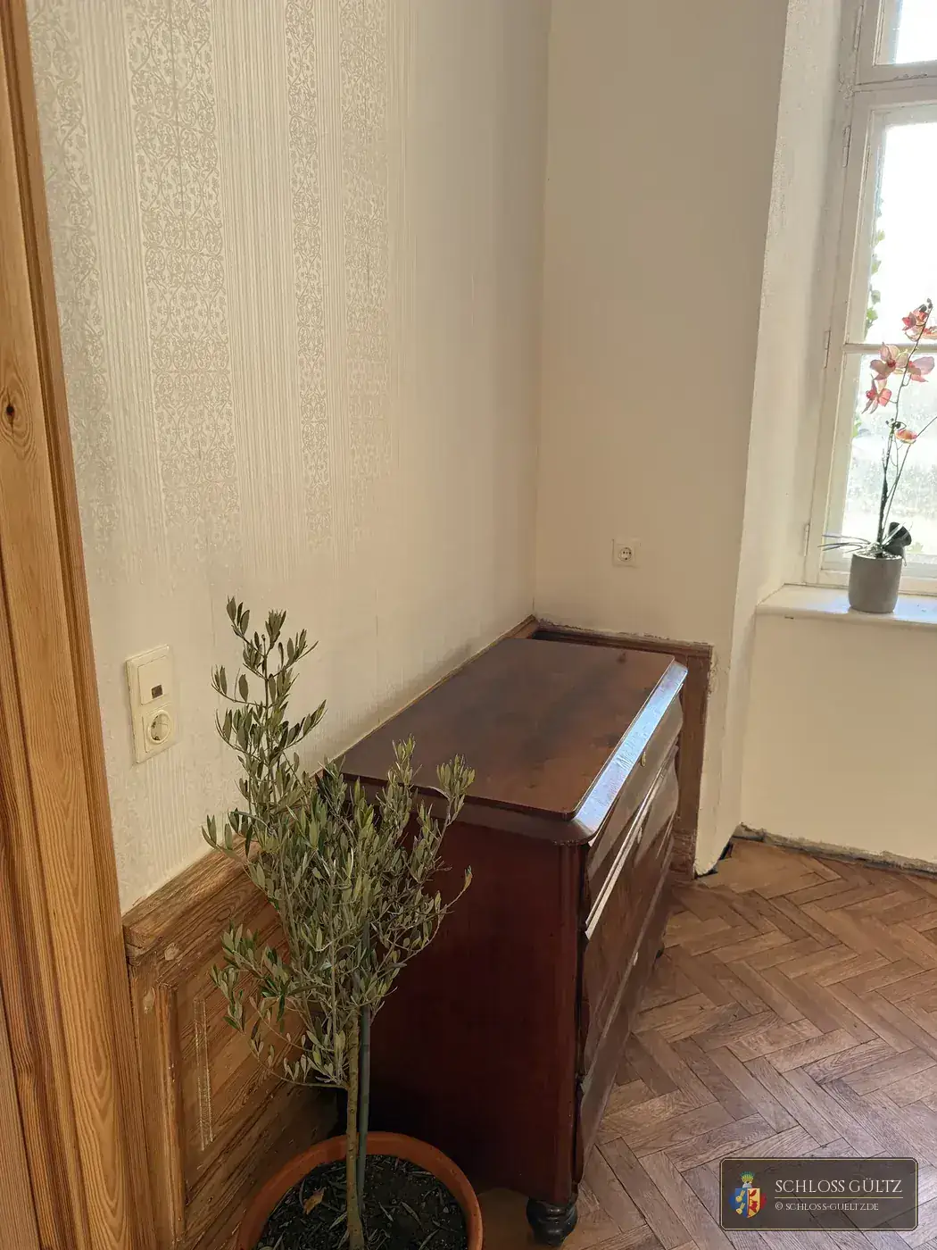 Mahoniowa komoda na parkiecie w jodełkę w Apartamencie Baronów