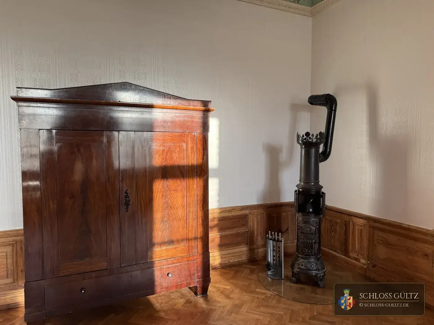 Szafa biedermeierowska i żeliwny piec w Apartamencie Baronów